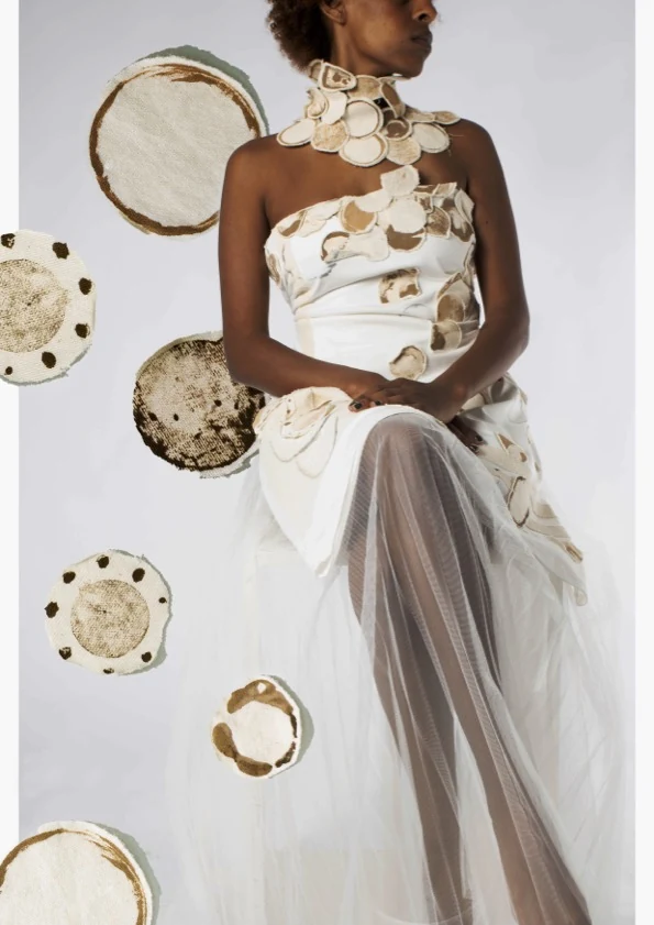 Seated model in a white garment constructed from circular forms